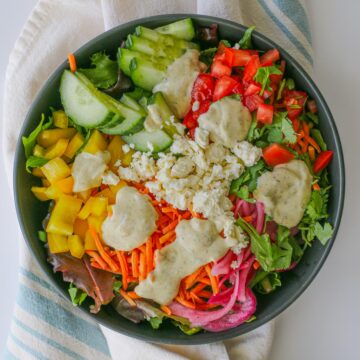 overhead shot of large salad with greek yogurt dressing and feta cheese.