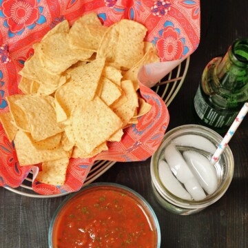 A bowl of salsa with basket of chips