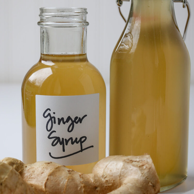 ginger syrup bottles next to hunk of ginger root.