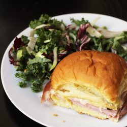 A sandwich on a plate, with kale salad