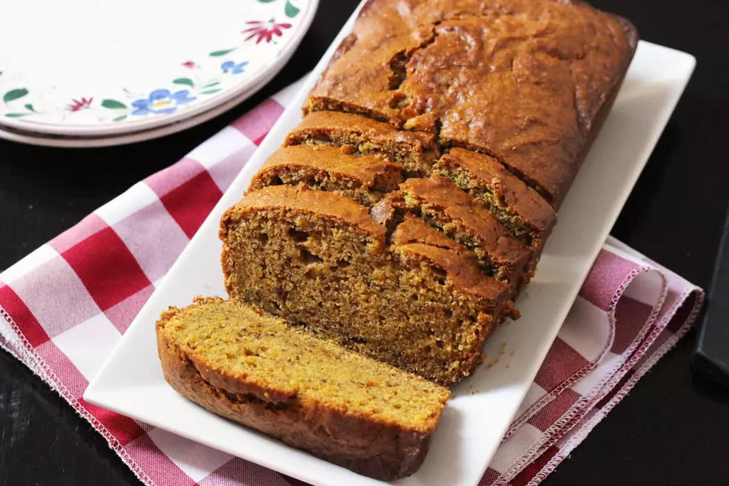 sliced loaf of pumpkin bread on tray with checked cloth