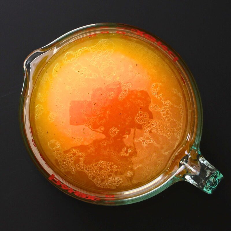 Creamy Hen Noodle Soup 4 chicken stock in large glass pitcher.