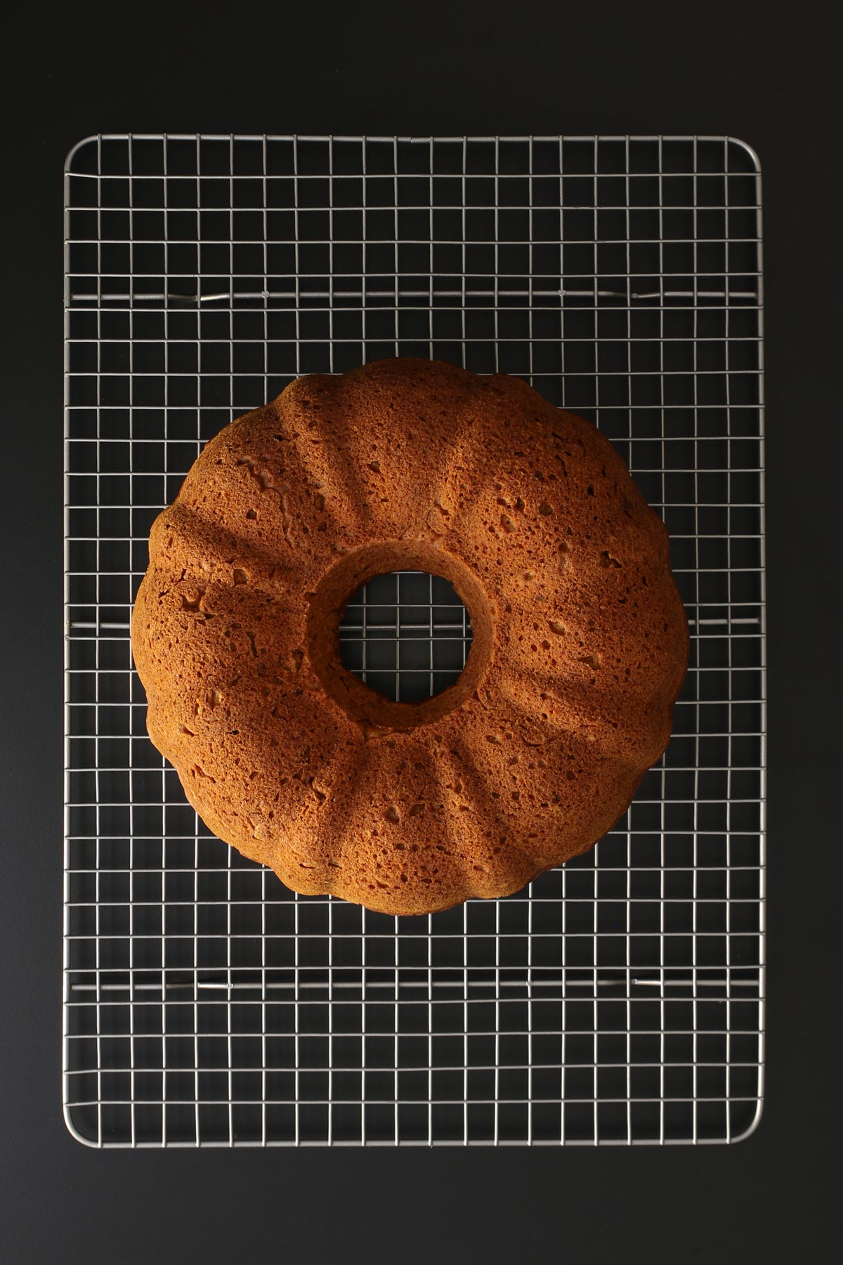 bundt cake cooling on wire rack on a black table top.