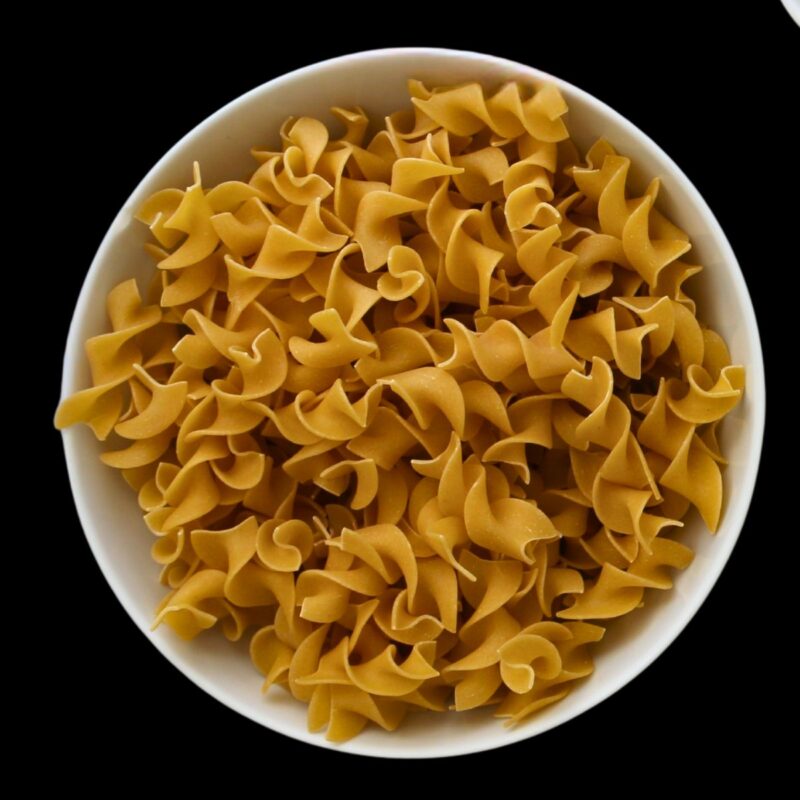 wide egg noodles in a white bowl.