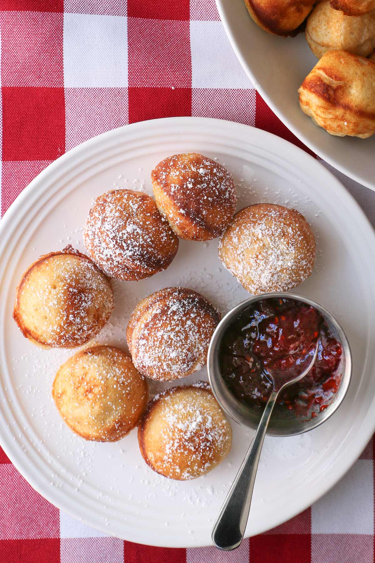 overhead shot of aebleskiver on plate with jam cup and spoon.