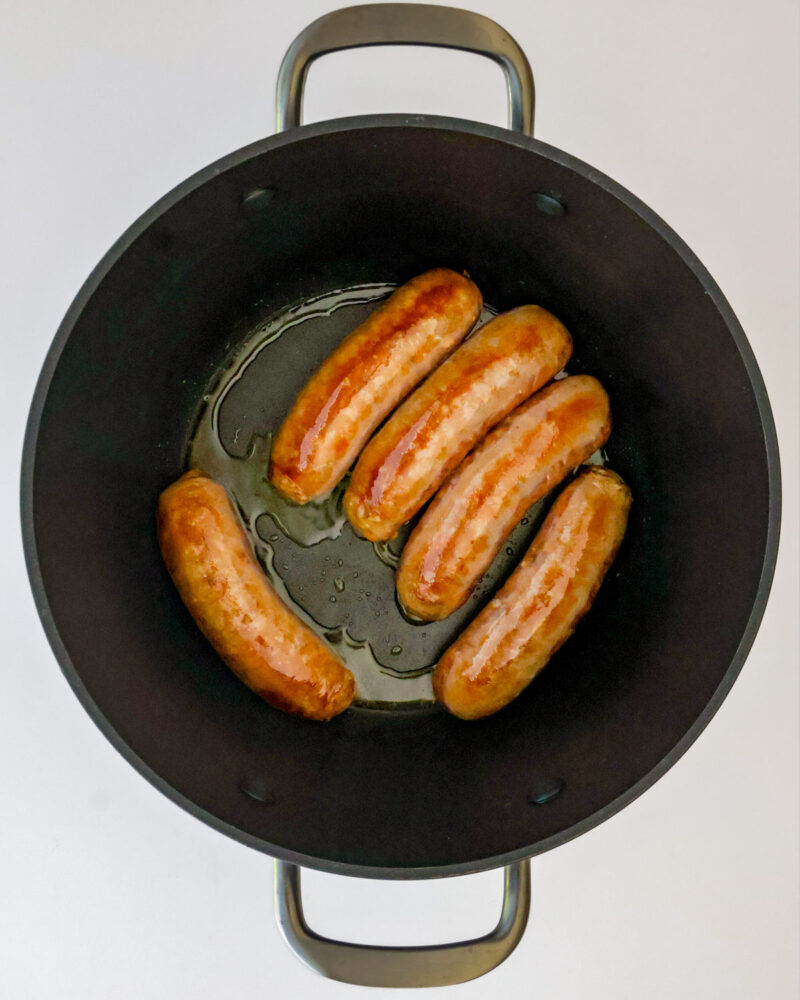 browning sausages in pot.