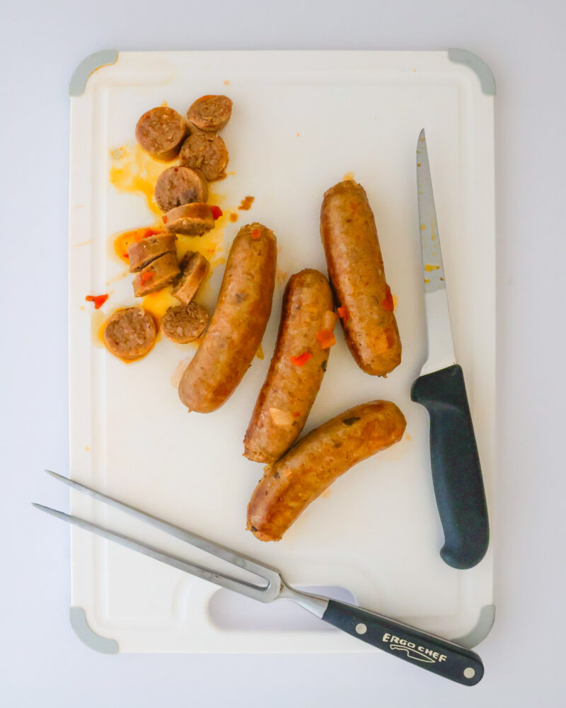 slicing sausages on cutting board. 