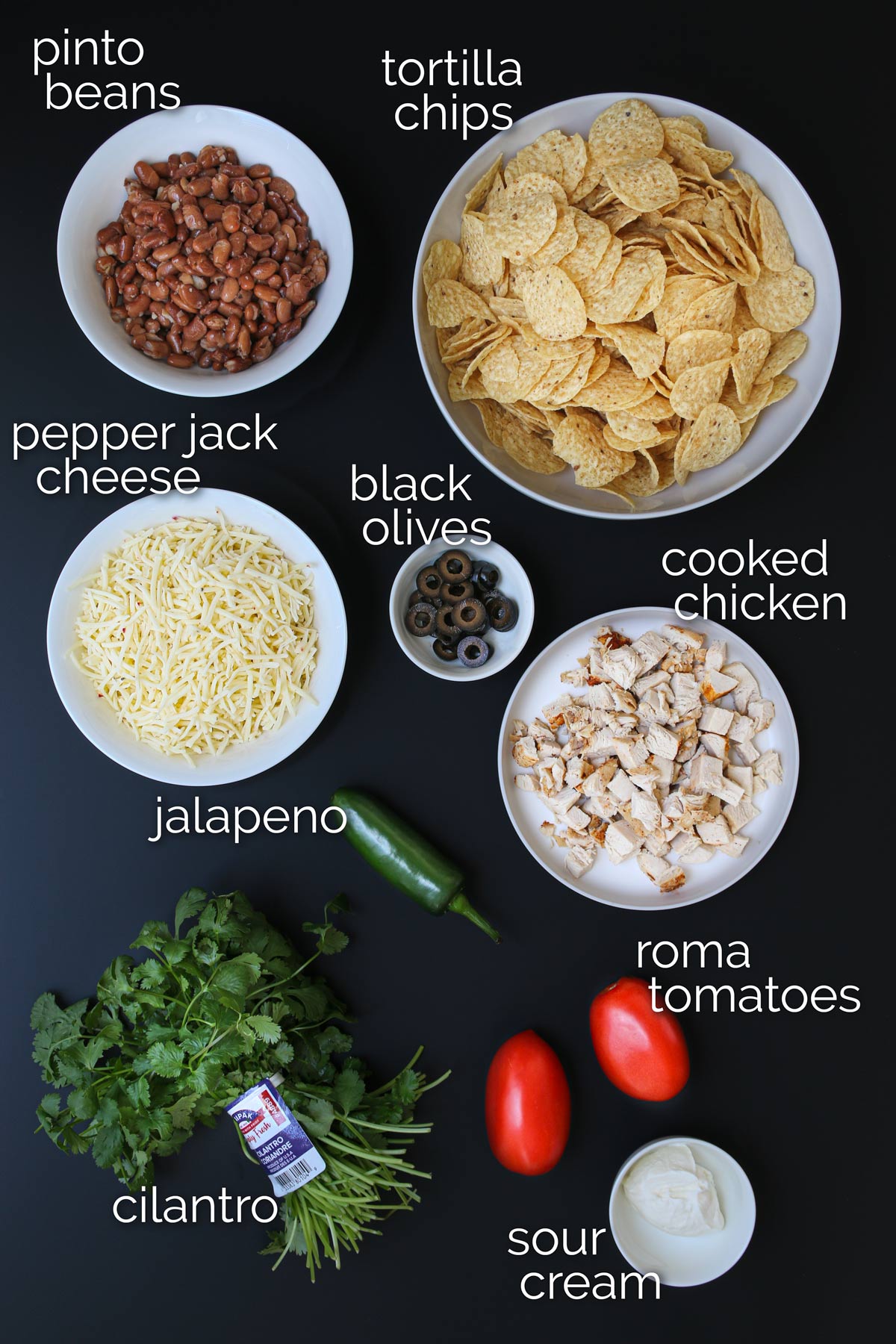 ingredients for sheetpan nachos laid out on black table.