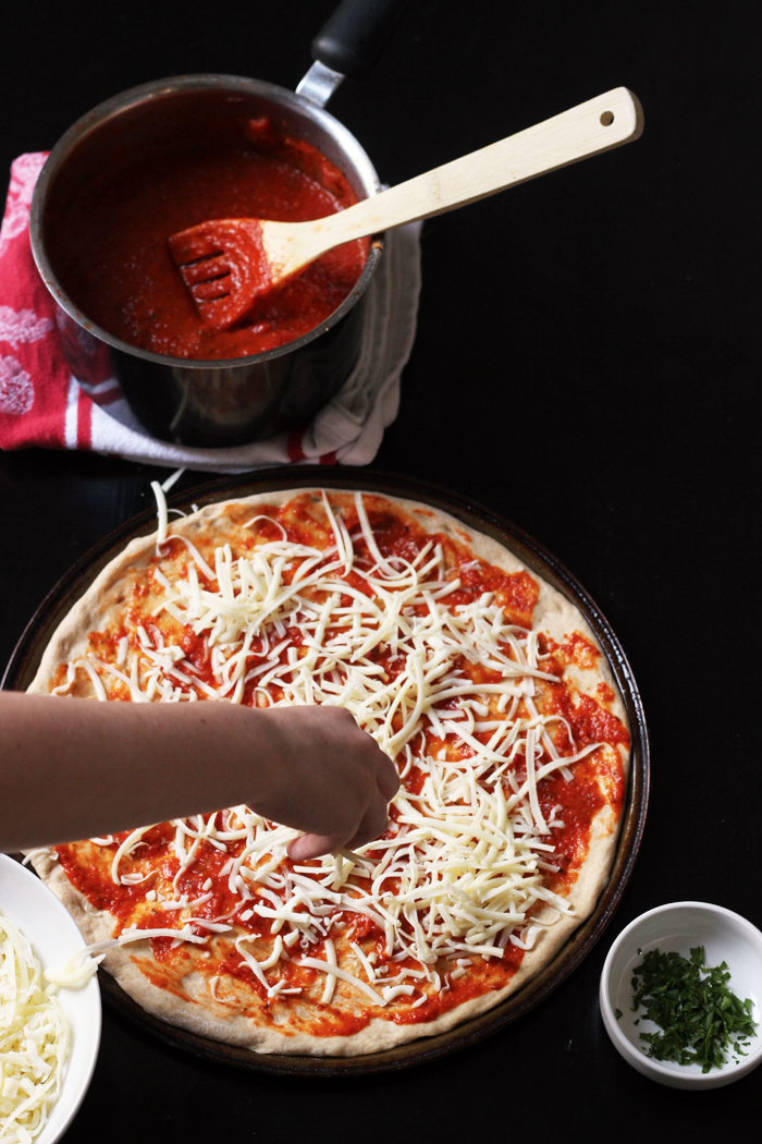 pizza being assembled and a pot of pizza sauce