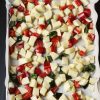 raw potato and pepper cubes on lined tray
