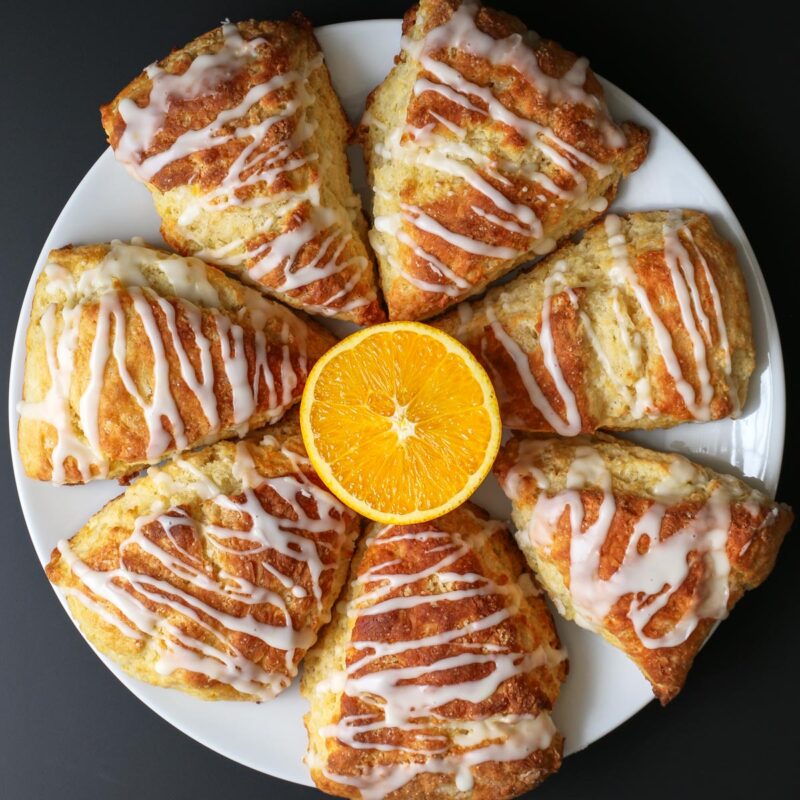 wedges of orange scone on a round platter around a half cut orange.