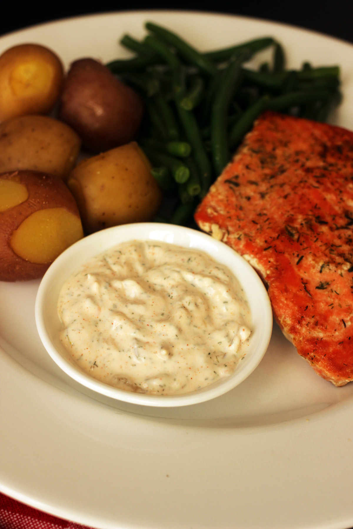 close-up of ramekin of tartar sauce on plate of fish.