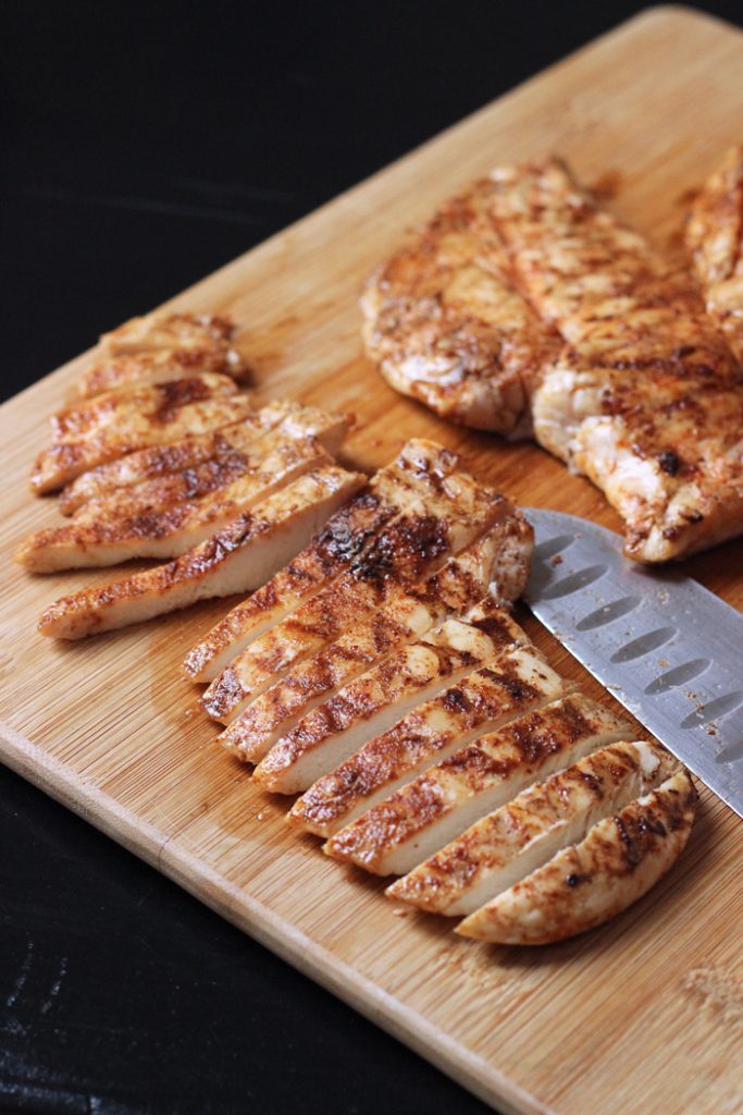 chicken breasts sliced on wooden cutting board