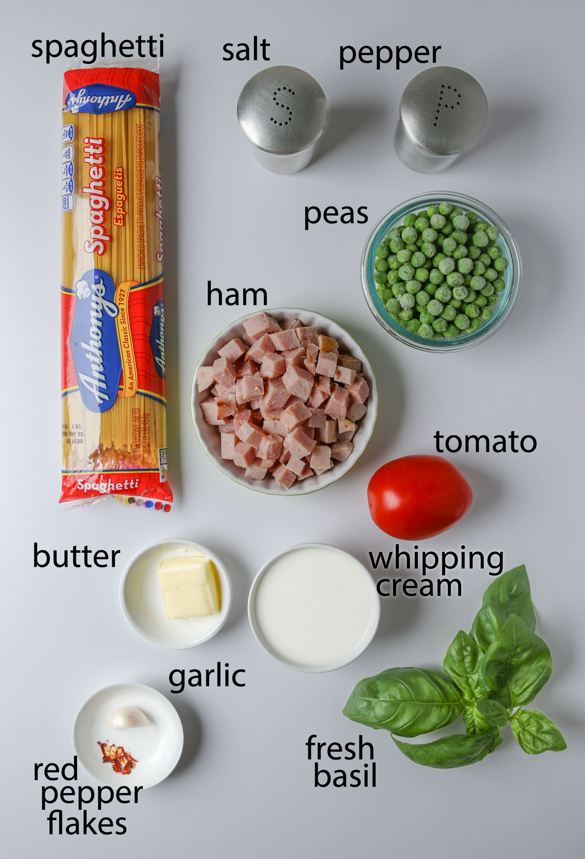 ingredients to make ham pasta, laid out on a white table.