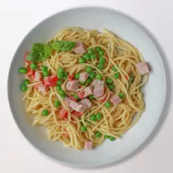 overhead shot of a bowl of creamy ham pasta with peas.