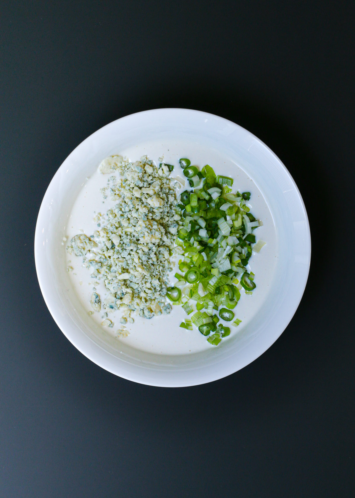 blue cheese crumbles and chopped green onion atop the surface of the buttermilk mixture.