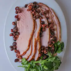 close up of platter of crockpot ham with cranberry and parsley garnish.