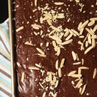 A sheet pan cake with chocolate frosting and slivered almonds