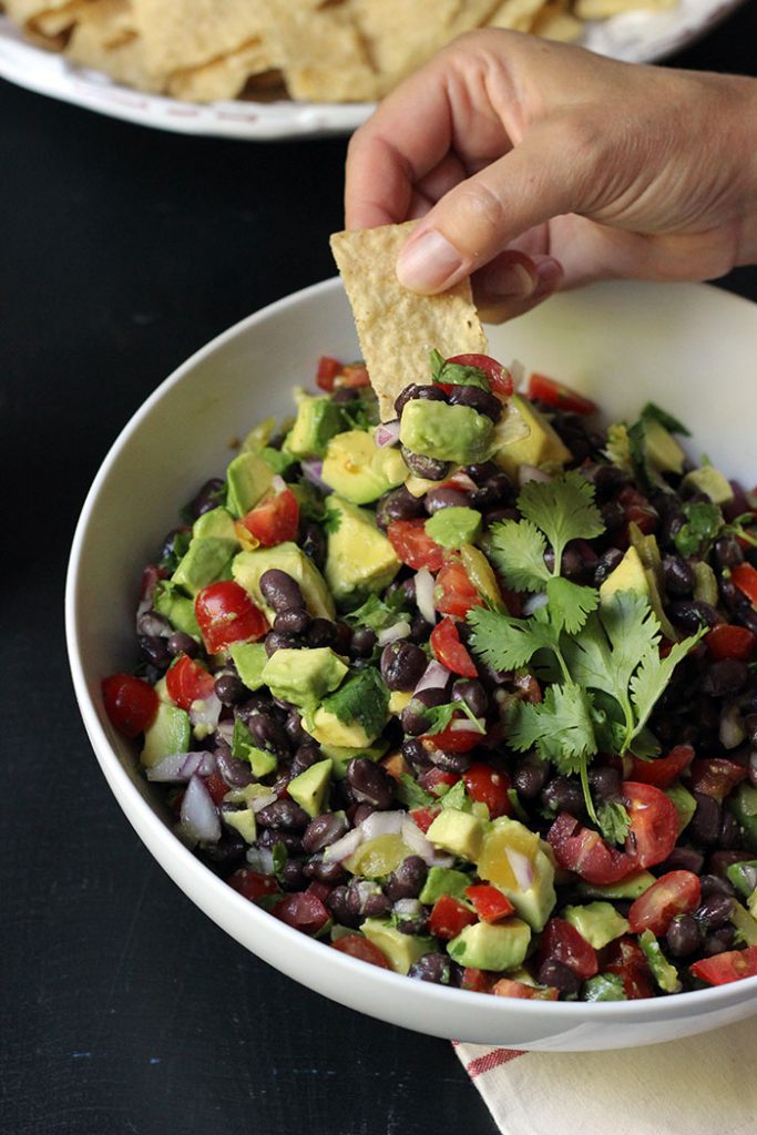 A person scooping chip into Santa Barbara Cowboy Caviar