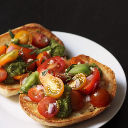 A plate of bruschetta toasts piled with tomatoes