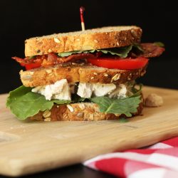 triple decker chicken salad club sandwich on board with checked cloth