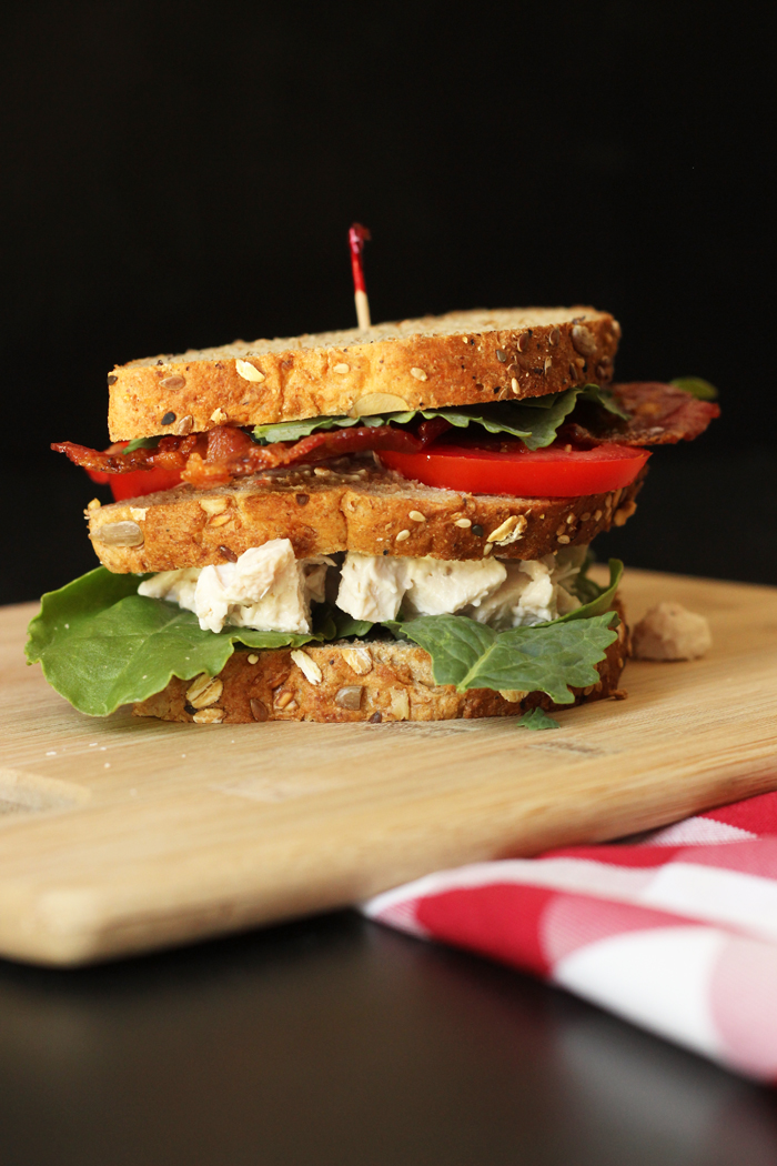 triple decker chicken salad club sandwich on board with checked cloth