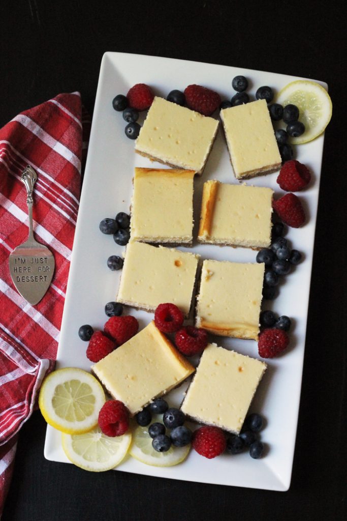 tray of cheesecake squares with fresh berries