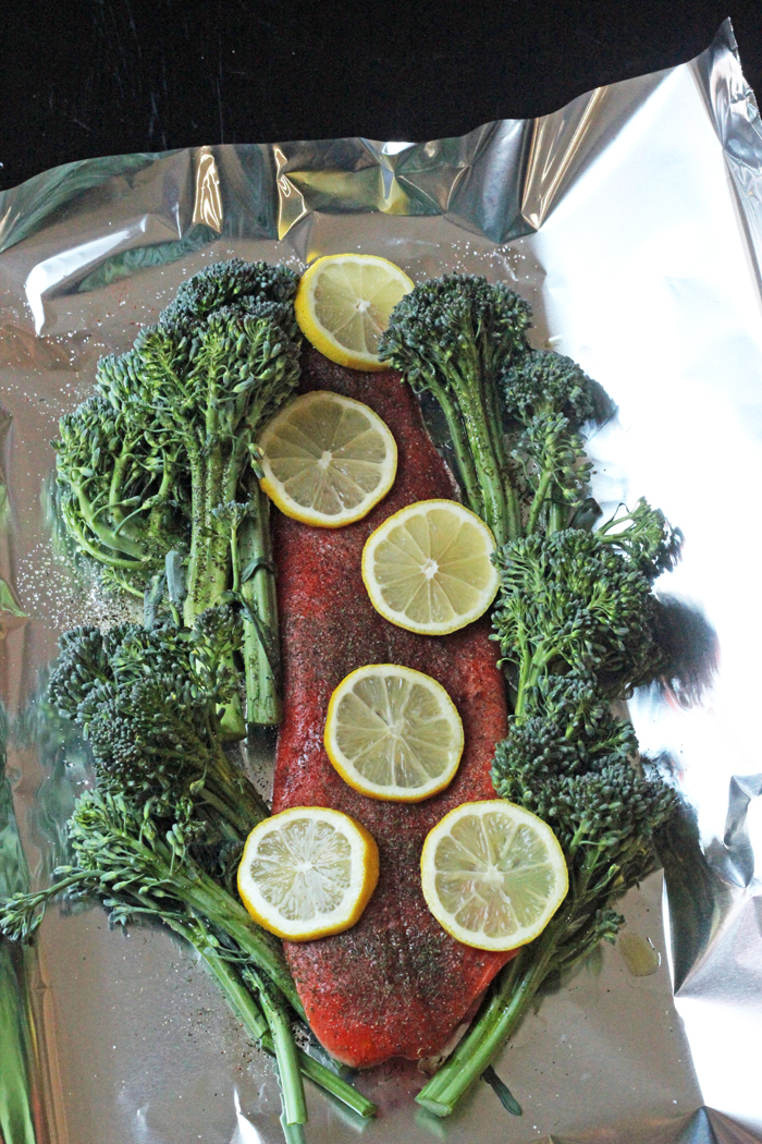 Salmon on tinfoil topped with lemon slices and broccolini
