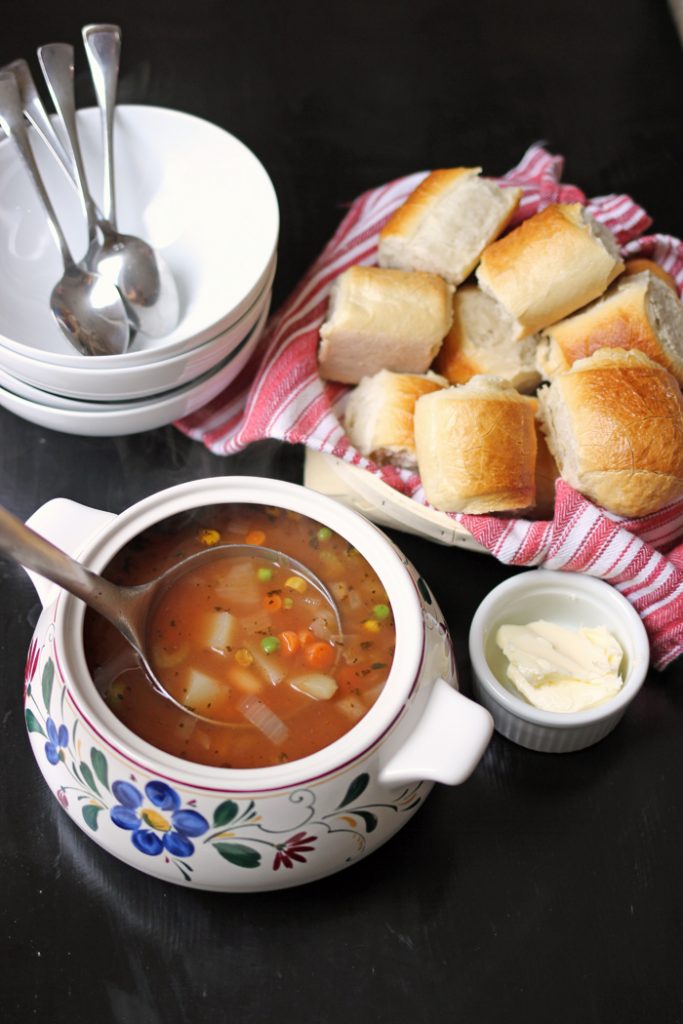 A tureen of soup on a table, with bread