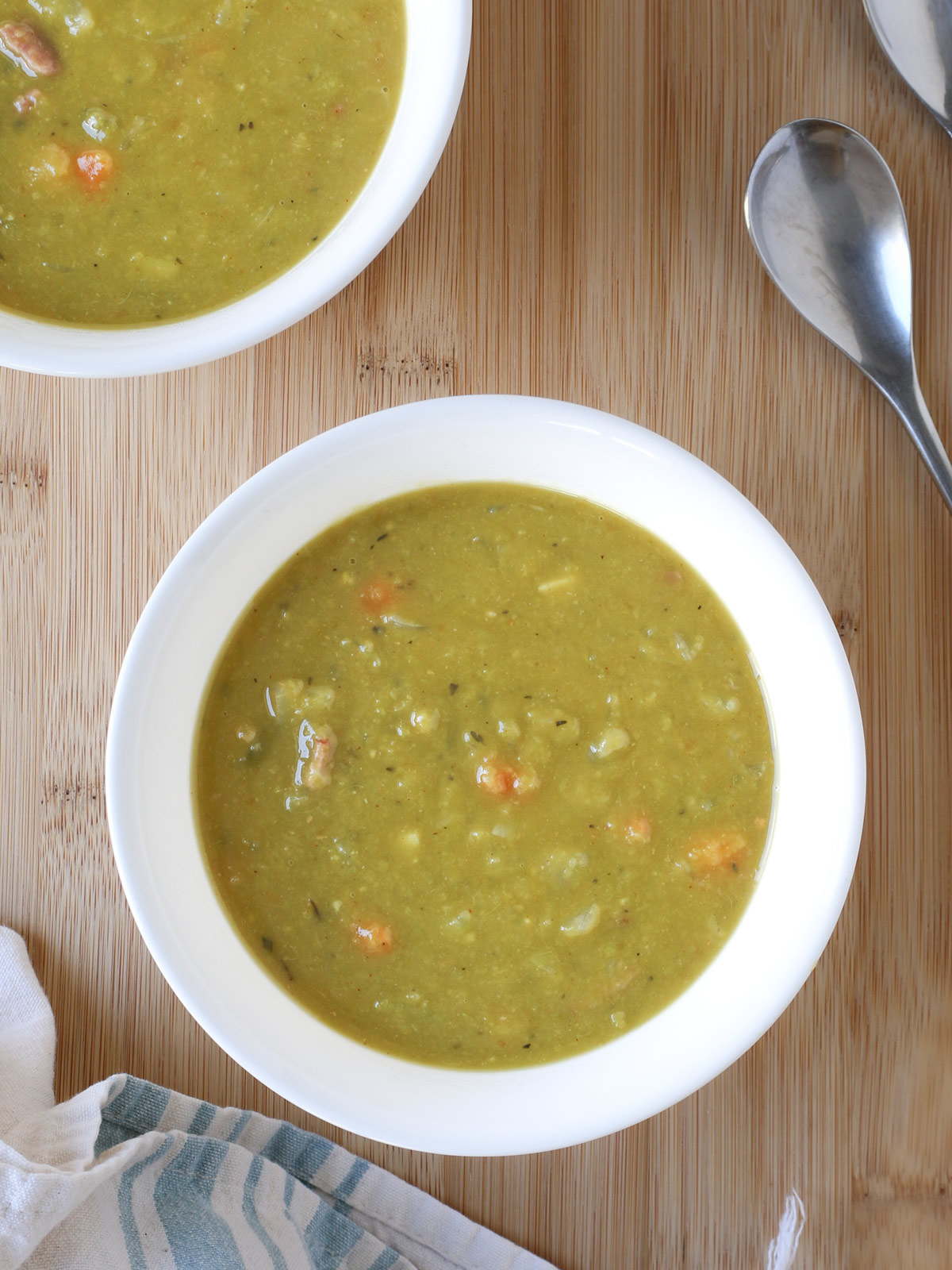 two bowls of split pea soup on a wood table.