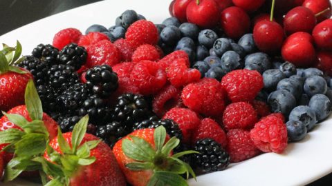 tray of berries with toppings on the side