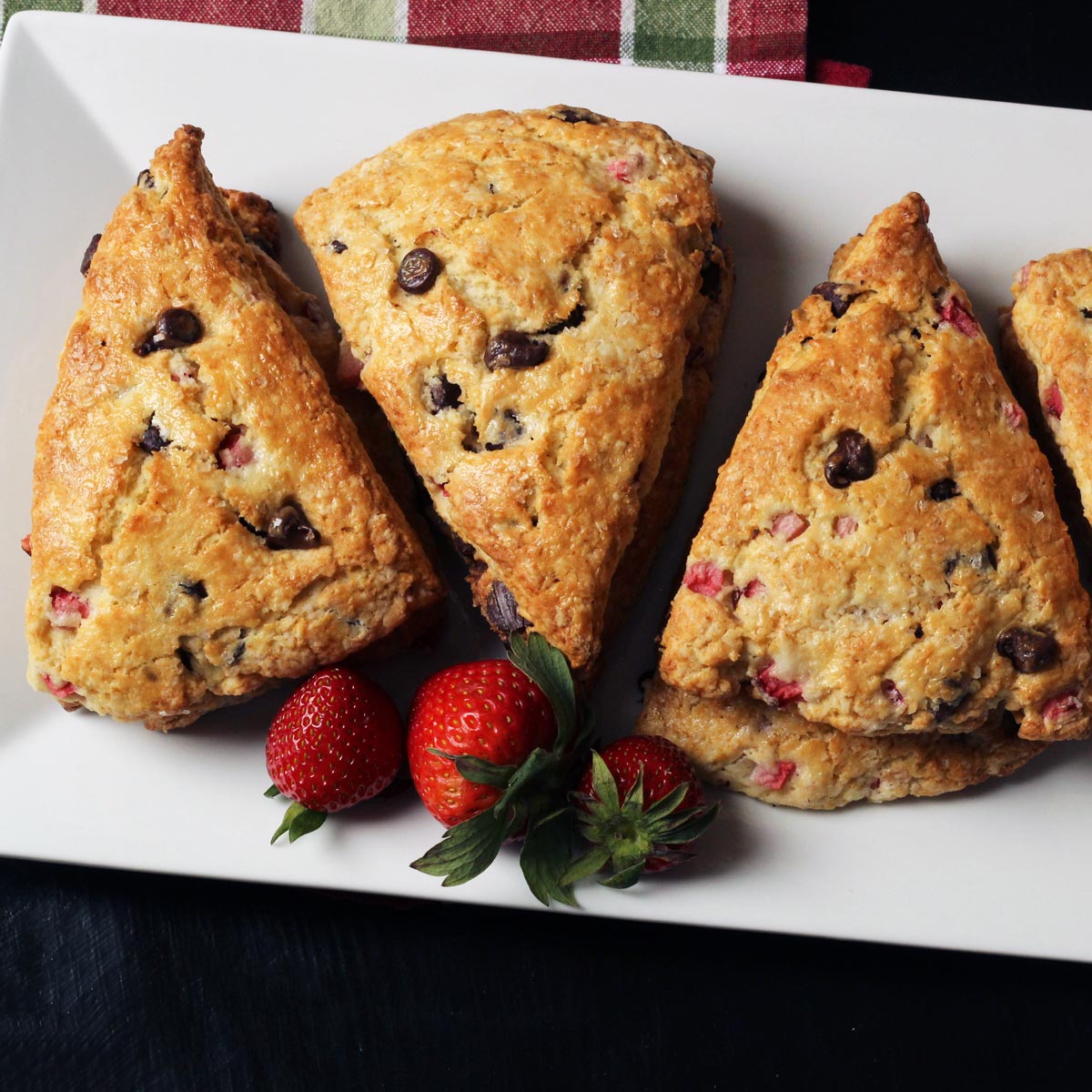 chocolate strawberry scones on platter with strawberries.