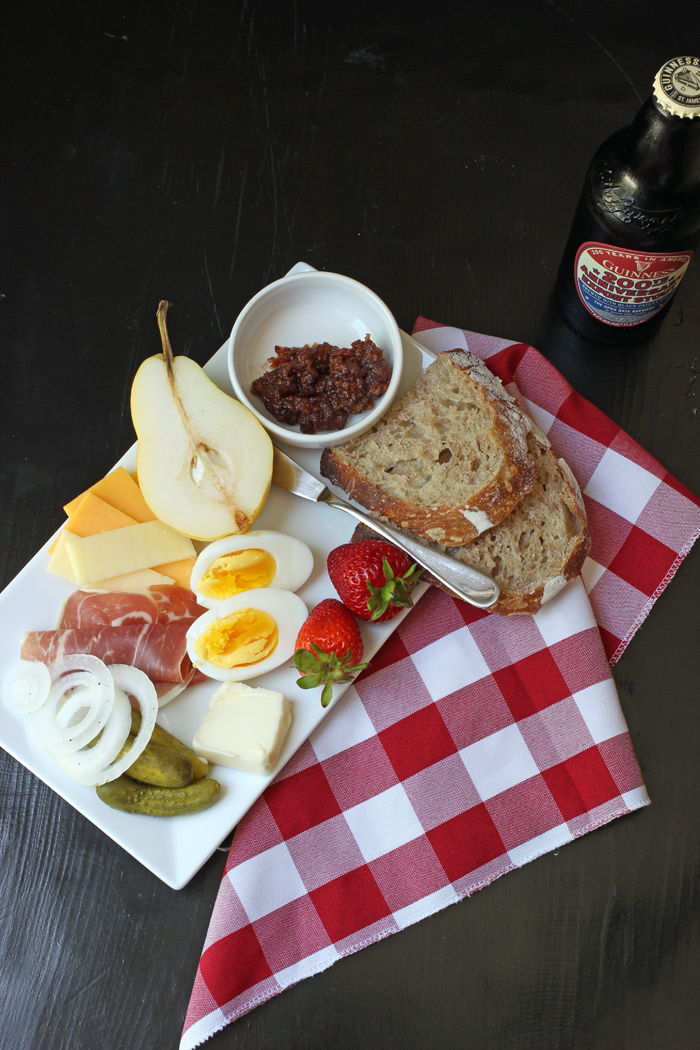 platter of meats, cheese, fruits and bread with a beer