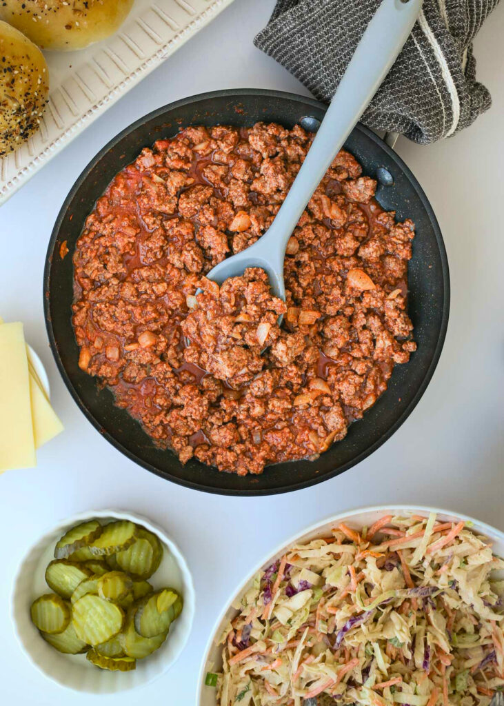 a skillet full of sloppy joe sauce surrounded by toppings and side dishes.