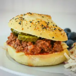 sloppy joe on plate with pickles.