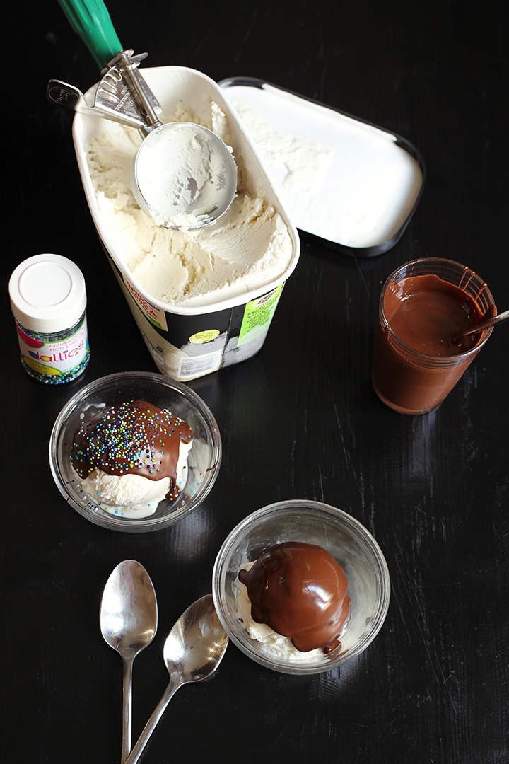 ice cream scooped into two bowls with magic shell and sprinkles