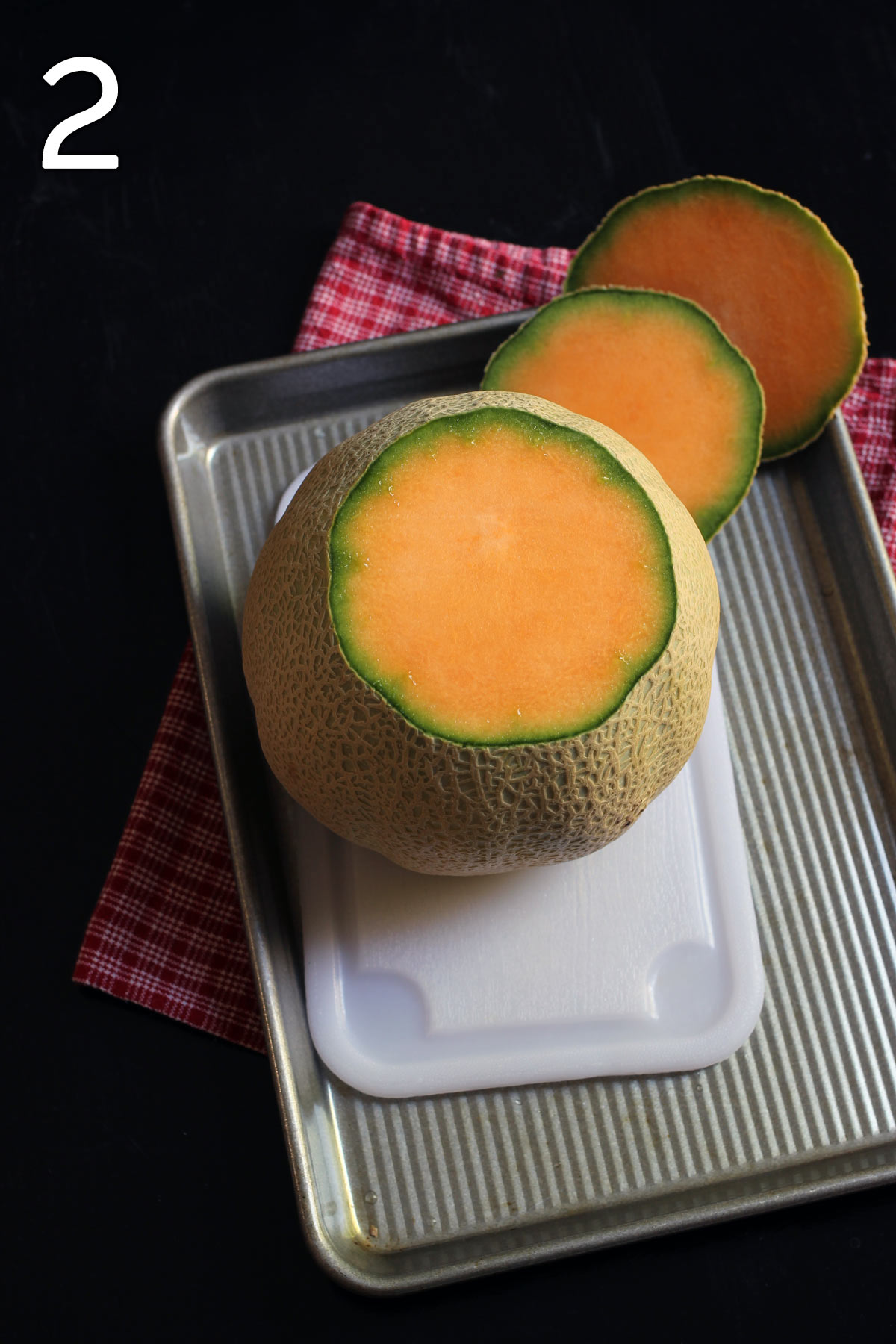 melon with ends cut off standing upright on cutting board within sheet pan.