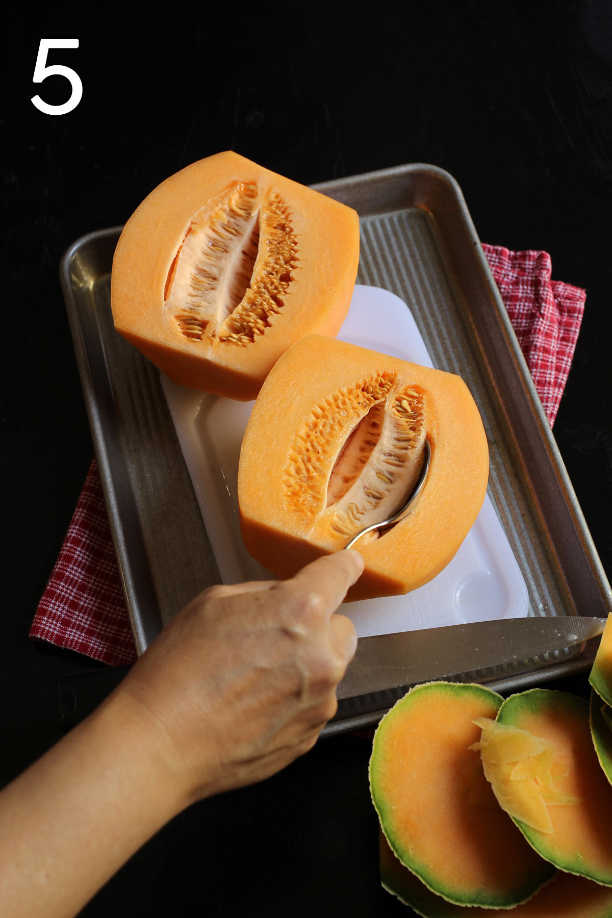 inserting spoon into center of melon to scrape out seeds.
