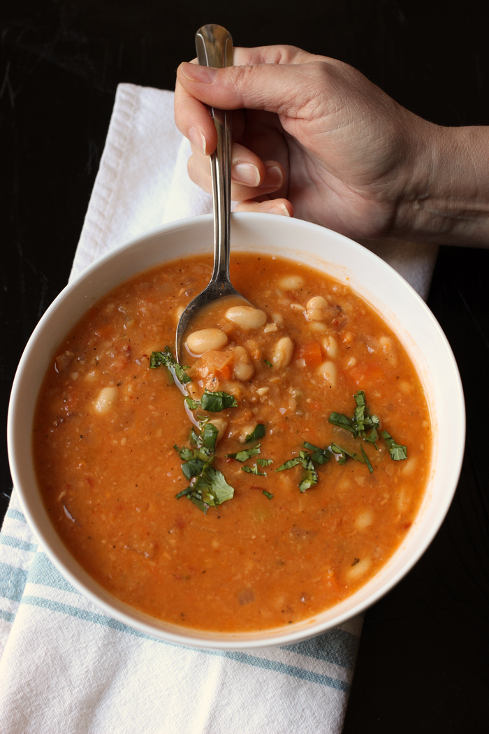 bowl of bean soup with hand and spoon