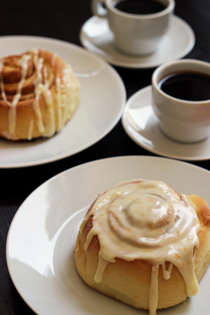 two glazed orange sweet rolls and two cups of espresso