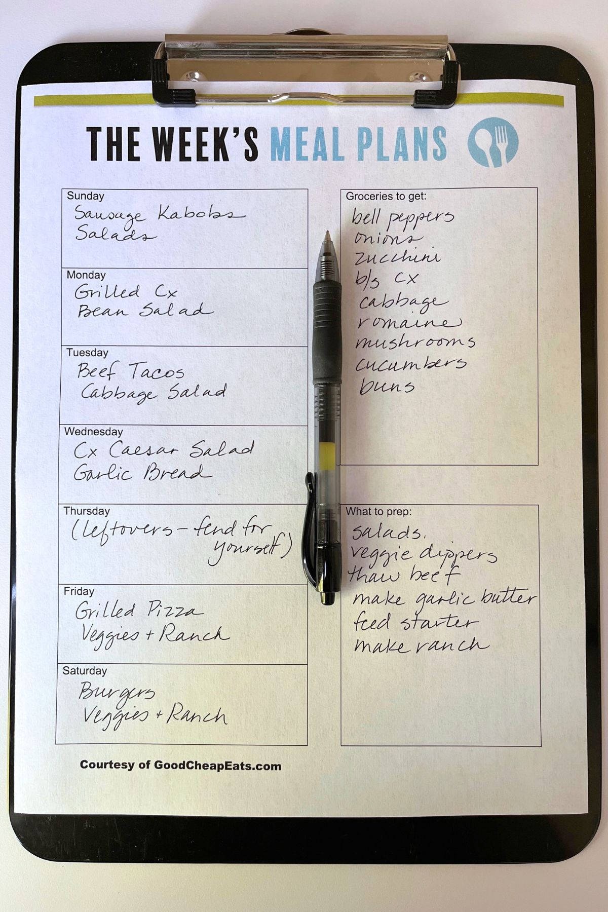 meal planner printable on clipboard on white table.