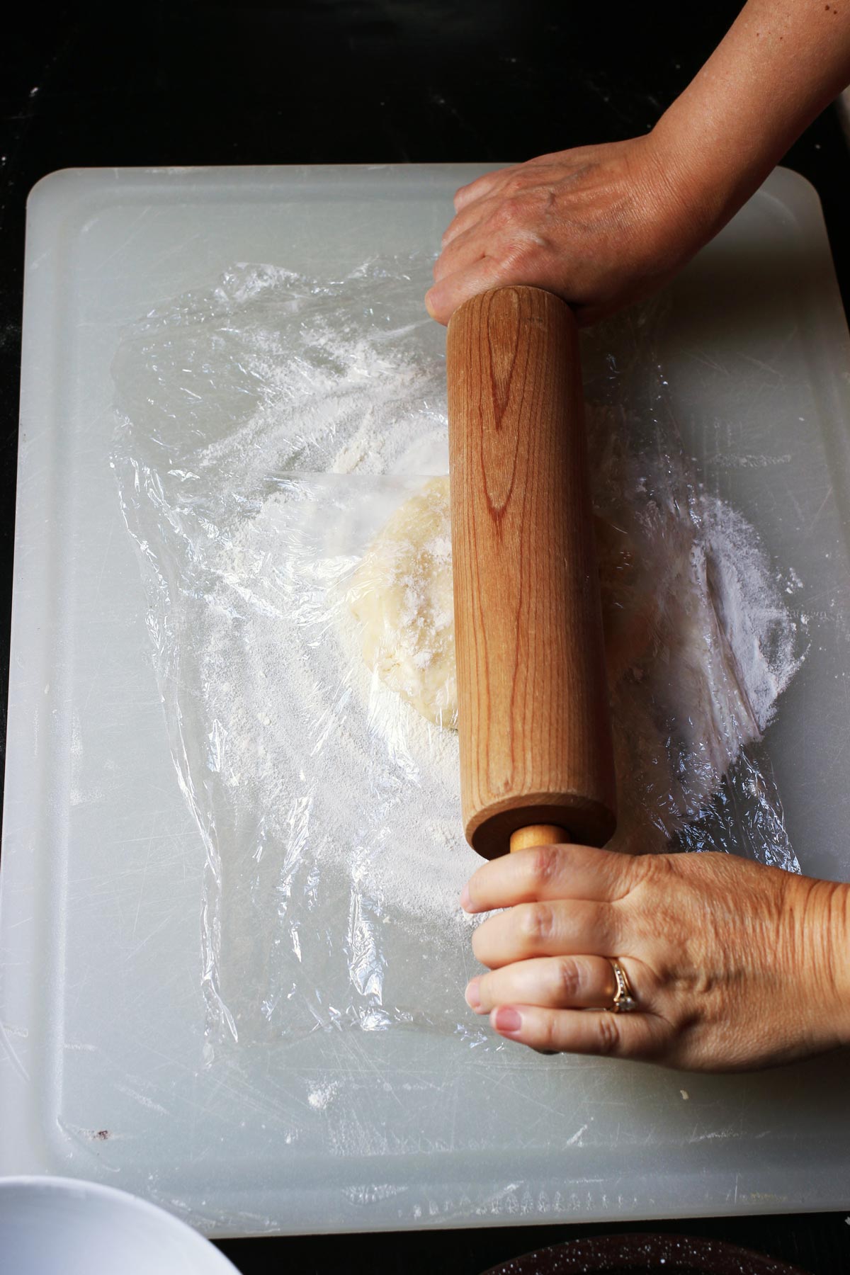 rolling pie dough with pin and plastic wrap