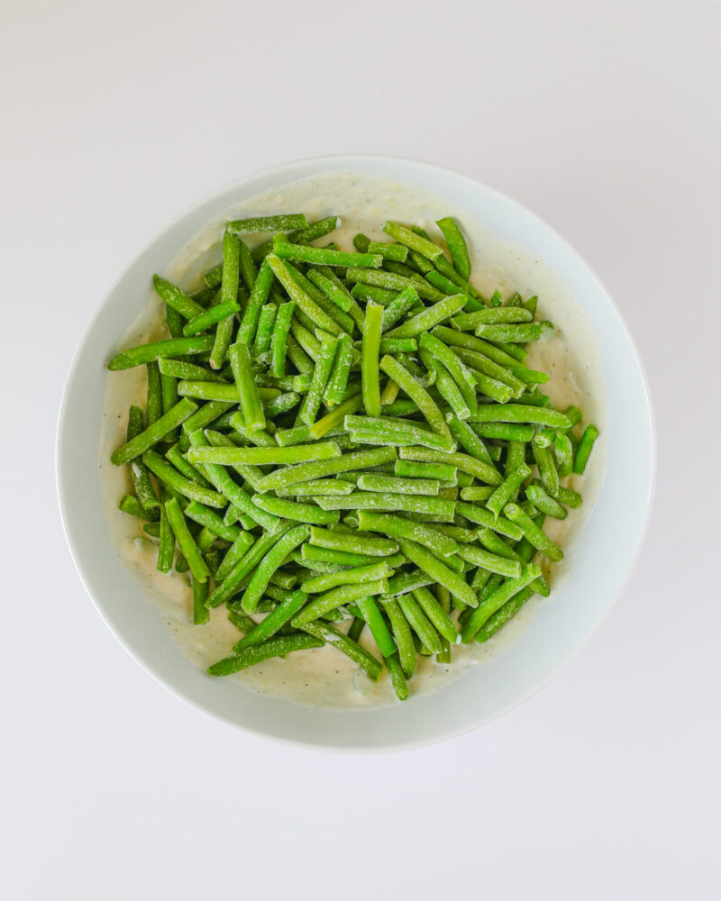 green beans added to the sauce in mixing bowl.