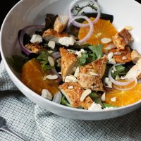 salad in white bowl with chicken and orange slices