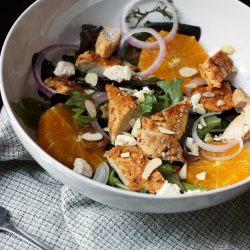 salad in white bowl with chicken and orange slices