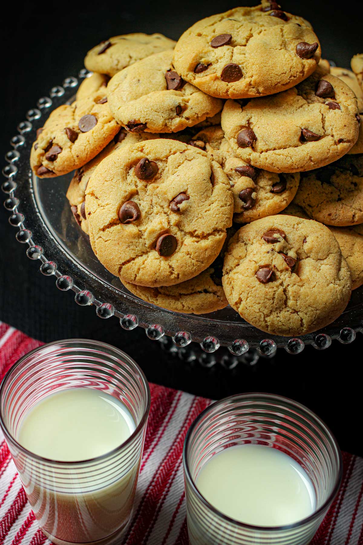 platter of chocolate chip cookies next to two glasses of milk.