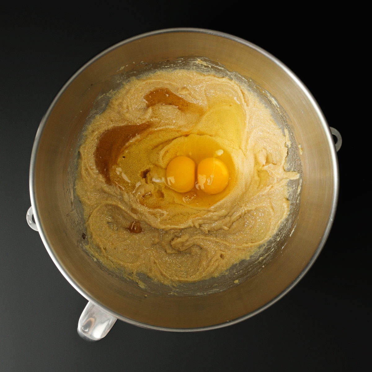 adding eggs and vanilla to mixture in bowl.
