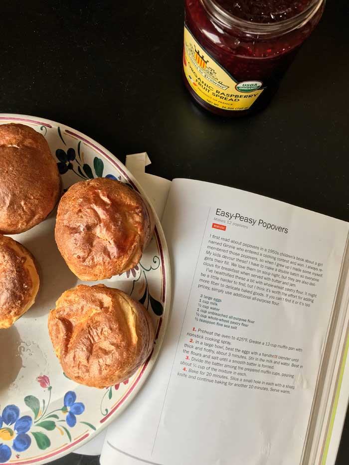 plate of popovers next to cookbook and jar of jam