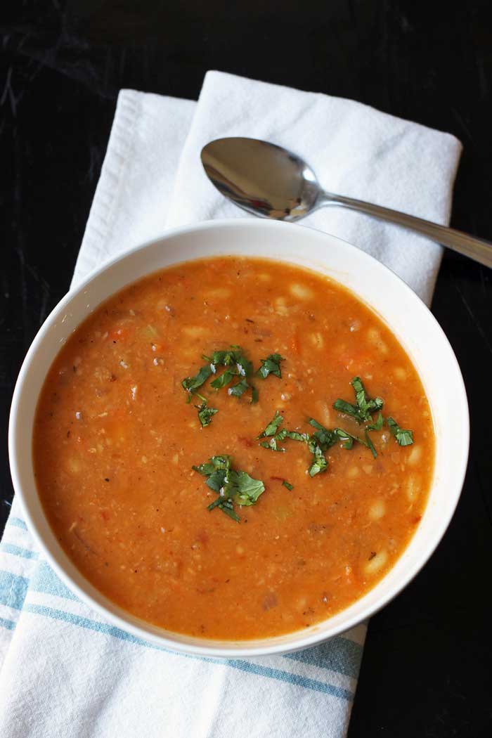 white bowl of bean soup with spoon and napkin