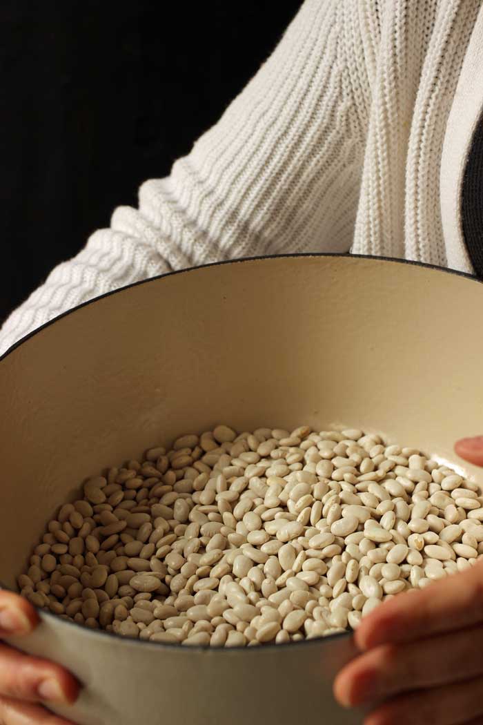 woman holding pot of dried white beans